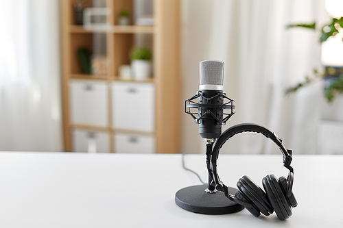 technology and audio equipment concept - headphones and microphone at home office or recording studio