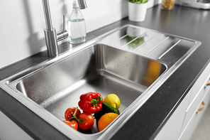 hygiene, food and safety concept - fruits and vegetables in stainless steel kitchen sink