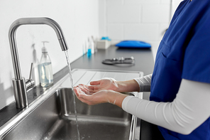 hygiene, health care and safety concept - close up of female doctor or nurse washing hands with liquid soap at hospital