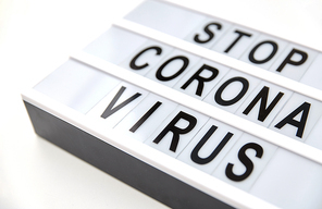 medicine, epidemic and healthcare concept - close up of lightbox with stop corona virus caution words on white background