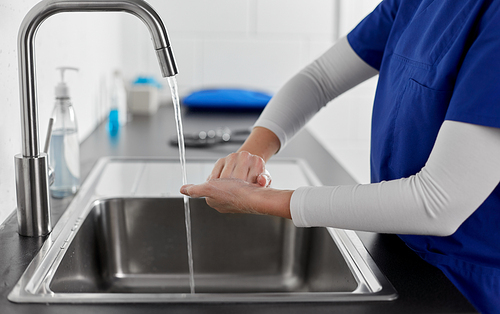 hygiene, health care and safety concept - close up of female doctor or nurse washing hands with liquid soap at hospital