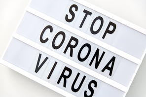 medicine, epidemic and healthcare concept - close up of lightbox with stop corona virus caution words on white background