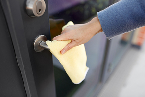 hygiene, health care and safety concept - close up of hand cleaning outdoor door handle surface with microfiber rag