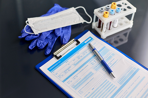 medicine, healthcare and diagnosis concept - close up of clipboard with medical report, beakers with blood test in holder, mask and gloves on table at hospital or laboratory