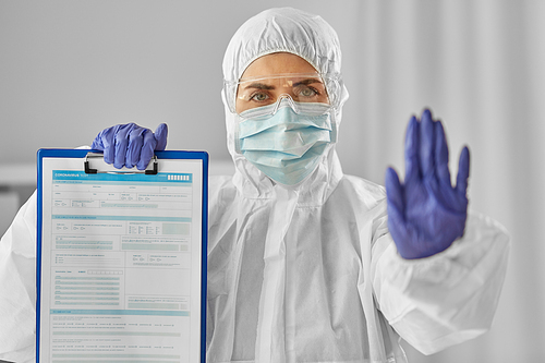 health safety, medicine and pandemic concept - close up of female doctor or scientist in protective wear, medical mask and goggles showing medical report on clipboard and stop gesture