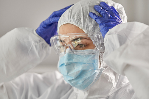 health safety, medicine and pandemic concept - close up of female doctor or scientist in protective wear, medical mask, goggles and gloves for protection from virus disease