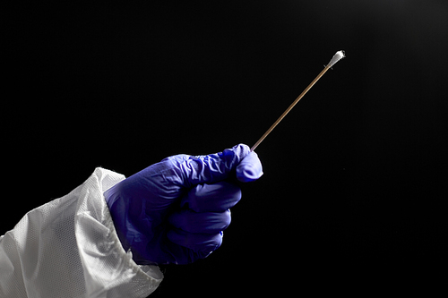 medicine, health and virus concept - close up of doctor's hand in medical glove holding cotton swab over black background