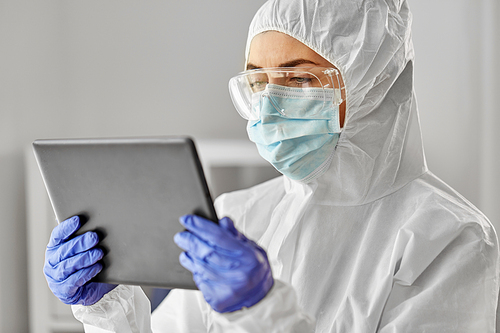 health safety, medicine and pandemic concept - close up of female doctor or scientist in protective wear, medical mask, gloves and goggles for protection from virus disease with tablet computer