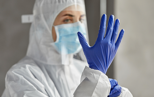 health safety, medicine and pandemic concept - close up of female doctor or scientist in protective wear, medical mask, face shield and gloves for protection from virus disease