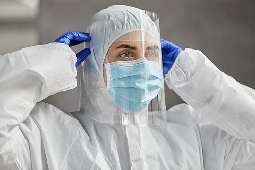 health safety, medicine and pandemic concept - close up of female doctor or scientist in protective wear, medical mask, face shield and gloves for protection from virus disease