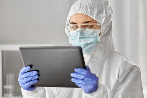 health safety, medicine and pandemic concept - close up of female doctor or scientist in protective wear, medical mask, gloves and goggles for protection from virus disease with tablet computer