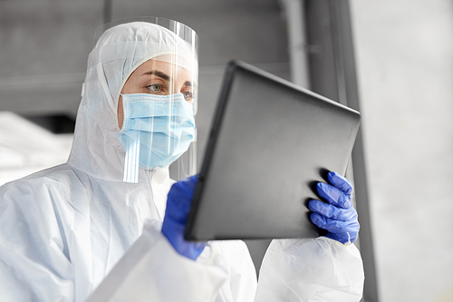 health safety, medicine and pandemic concept - close up of female doctor or scientist in protective wear, medical mask, gloves and face shield for protection from virus disease with tablet computer