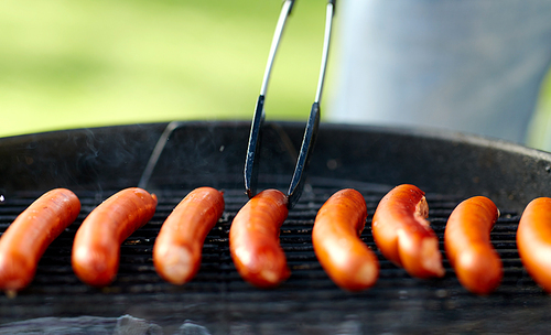 cooking, barbecue and food concept - close up of meat sausages roasting on hot brazier grill