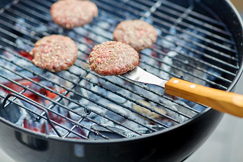 cooking, barbecue and fast food concept - close up of burger meat cutlets roasting on brazier grill outdoors