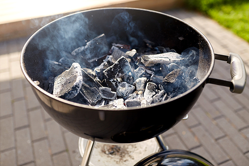 cooking, heat and fire concept - close up of charcoal smoldering in brazier outdoors