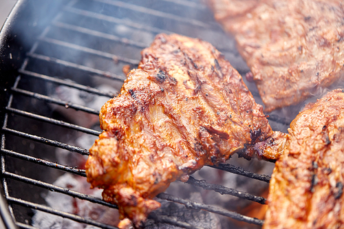 cooking, culinary and food concept - close up of barbecue meat roasting on brazier grill outdoors
