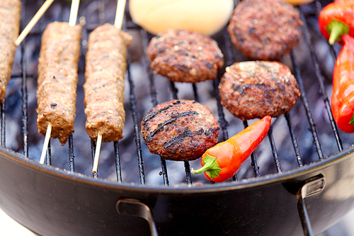 cooking, barbecue and food concept - close up of shish kebab meat, s on bamboo skewers, burger buns and cutlets roasting on brazier grill