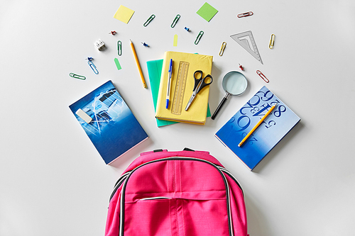 education and learning concept - pink backpack with books and school supplies on table