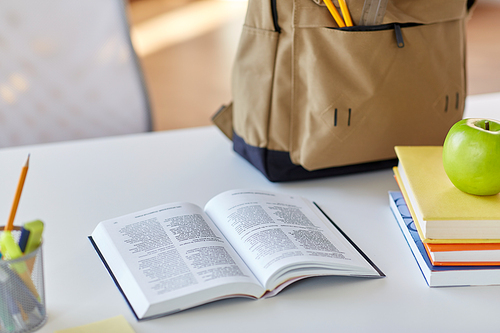 education and learning concept - close up of books, apple and school supplies on table at home