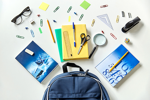 education and learning concept - blue backpack with books and school supplies on table