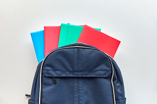 school, education and learning concept - backpack with notebooks on table