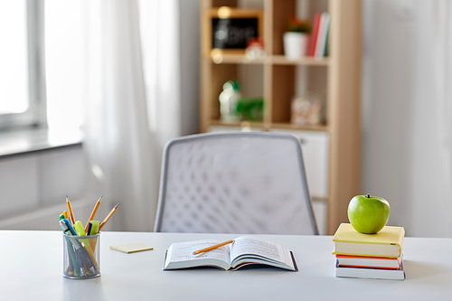 education and learning concept - books, apple and school supplies on table at home