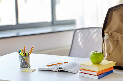 education and learning concept - books, apple and school supplies on table at home