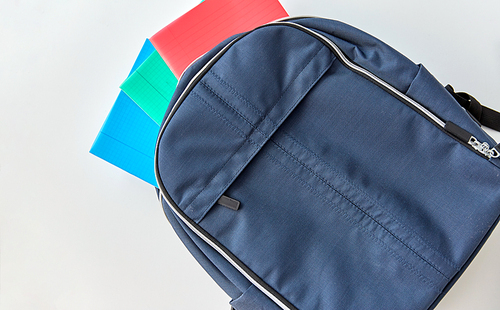 school, education and learning concept - backpack with notebooks on table