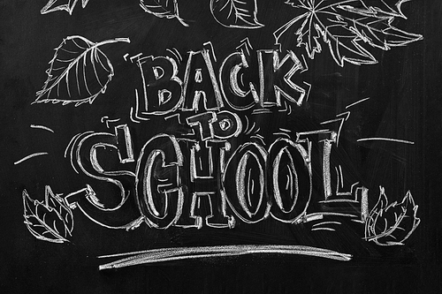 backgrounds, education and learning concept - back to school words and autumn leaves drawn with chalk on black chalkboard