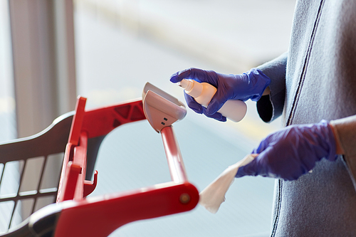 hygiene, health care and safety concept - close up of woman in gloves cleaning outdoor door handle with hand sanitizer and tissue