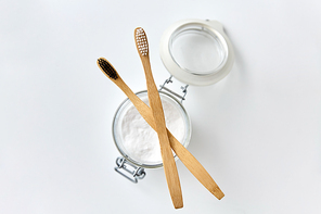 dental care, sustainability and eco living concept - washing soda in glass jar and wooden toothbrushes on white background