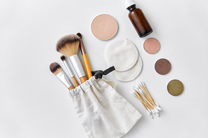 natural cosmetics and eco living concept - wooden make up brushes, cotton pads and swabs, eye shadows and essential oil or serum on white background