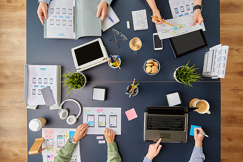 business, people and team work concept - team of startuppers with gadgets and papers working at office table