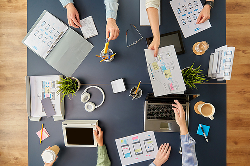 business, people and team work concept - team of startuppers with gadgets and papers working at office table