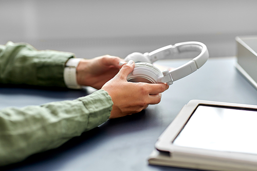 business, technology and people concept - close up of hands with headphones at office