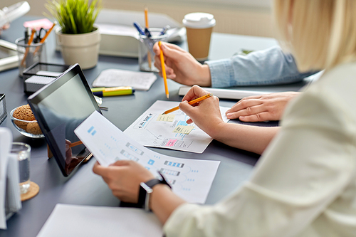 business, people and team work concept - close up of startuppers with gadgets and papers working at office table