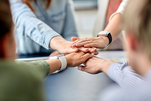 cooperation, corporate and team work concept - close up of business team stacking hands at office