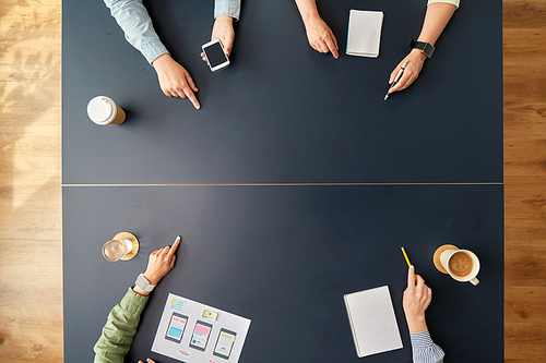 business, people and team work concept - team of startuppers with gadgets and papers pointing fingers to something on office table