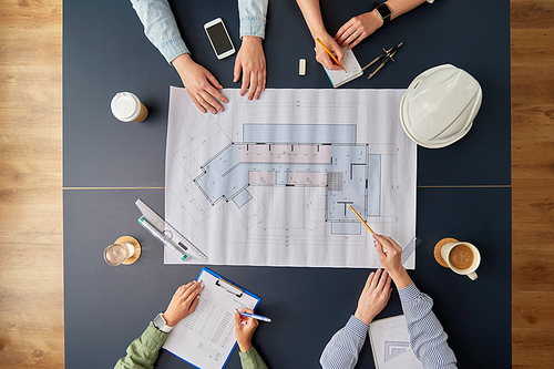 construction business, architecture and team work concept - team of architects with blueprint, gadgets and papers working at office table