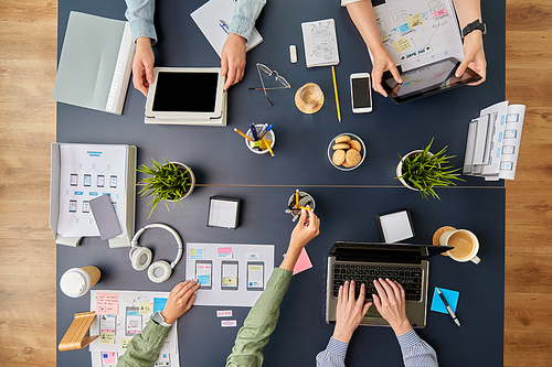 business, people and team work concept - team of startuppers with gadgets and papers working at office table