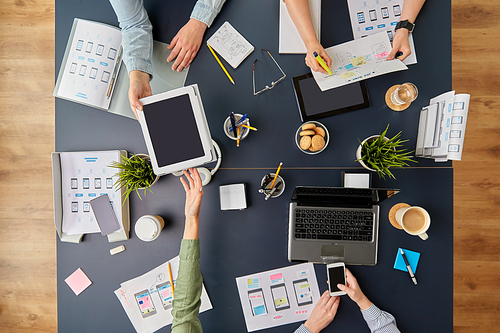 business, people and team work concept - team of startuppers with gadgets and papers working at office table