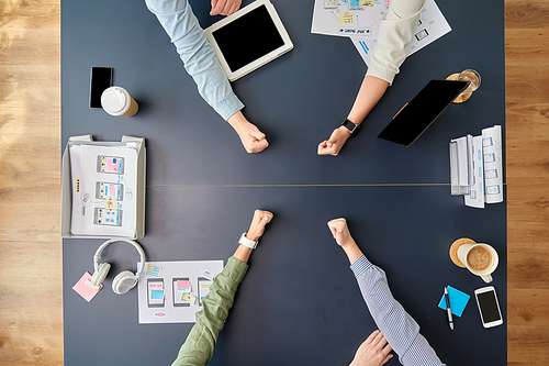 business, people and team work concept - team of startuppers with gadgets and papers showing thumbs up at office table