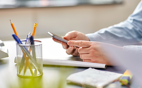 business, technology and people concept - close up of hands with using smartphone at office