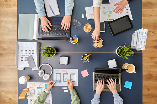 business, people and team work concept - team of startuppers with gadgets and papers working at office table