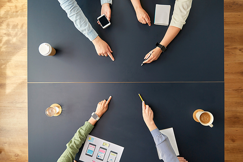 business, people and team work concept - team of startuppers with gadgets and papers pointing fingers to something on office table