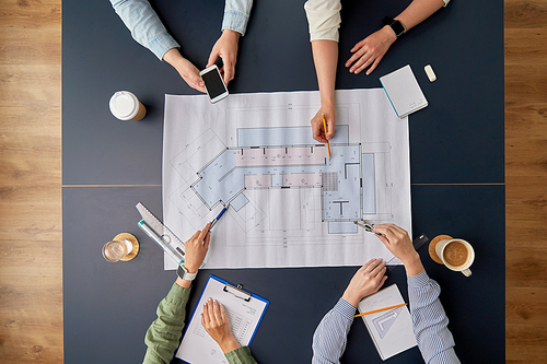 construction business, architecture and team work concept - team of architects with blueprint, gadgets and papers working at office table