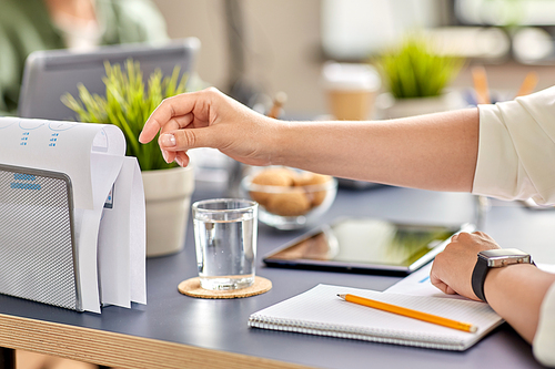 business, education and people concept - close up of hand reaching to paper in organizer at office