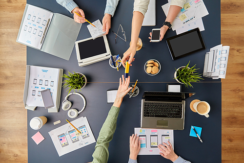 business, people and team work concept - team of startuppers with gadgets and papers working at office table