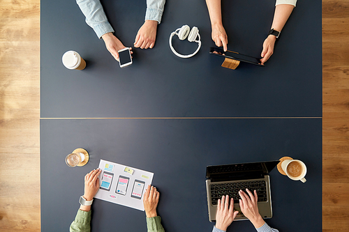 business, people and team work concept - team of startuppers with gadgets and papers working at office table