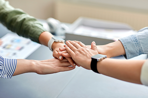 cooperation, corporate and team work concept - close up of business team stacking hands at office